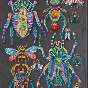 May include: A collection of beaded insect art pieces, including beetles and butterflies, in various sizes and colors. The artwork features intricate beadwork in shades of blue, green, yellow, and pink, set against a dark gray background.