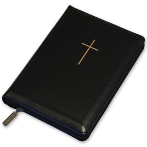 May include: Black Bible featuring a gold cross emblem on the front. It has a zip closure and a metallic zip pull. The cover is likely made of leather or a similar material.
