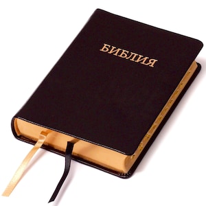 Könnte beinhalten: Ein schwarzes, ledergebundenes Buch mit goldenen Schnittkanten und einem goldenen Lesezeichen aus Satinband. Der Titel "Библия" ist in Gold auf dem Einband gedruckt.