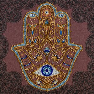 Peut inclure: Un motif de main de Hamsa perlé, orné de perles dorées, bleues et blanches. Le motif central de l'œil est mis en évidence. Le fond est de couleur mauve avec un motif cachemire.