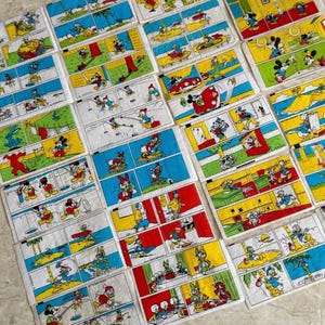 May include: A collection of vintage comic strip panels featuring Mickey Mouse, Donald Duck, and other Disney characters. Each panel has a colorful background with scenes of the characters in various adventures. The panels are arranged on a light-colored surface.