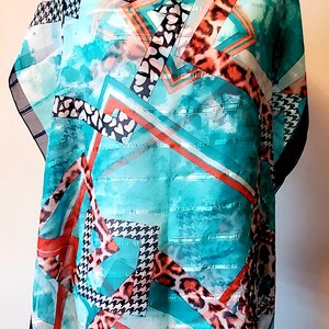 May include: A lightweight scarf featuring a vibrant turquoise watercolour background with a geometric pattern of orange lines, black and white houndstooth squares, leopard print bands, and small heart shapes, finished with a dark blue fringe hem.