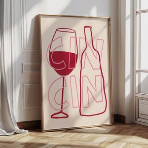 Puede incluir: Impresión artística enmarcada con un contorno de copa de vino y botella en rosa y rojo sobre un fondo crema. La palabra "GIN" está superpuesta a la imagen en rosa. La obra de arte se exhibe en una habitación con ventana y suelo de madera.
