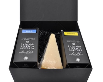 Könnte beinhalten: Eine schwarze Geschenkbox mit einem geöffneten schwarzen Deckel, die einen Keil Parmesan und zwei Flaschen Balsamico-Essig enthüllt. Die Flaschen sind mit "La Secchia Antica Acetaia" beschriftet und haben ein blaues und gelbes Etikett.