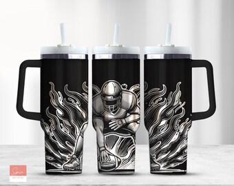 May include: A black and silver stainless steel tumbler with a handle and a straw. The tumbler features a graphic of a football player running with the ball, surrounded by flames.