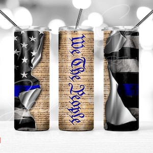 May include: Three stainless steel tumblers featuring a design of the American flag, a blue line, and the text "We The People" on a parchment background.