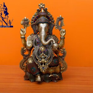 Puede incluir: Una estatua dorada de Ganesha, el dios hind&uacute; de la sabidur&iacute;a y la prosperidad, con intrincados detalles y piedras preciosas de colores. La estatua est&aacute; sentada en un trono de loto y tiene una trompa, cuatro brazos y una cabeza grande.