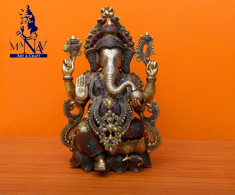Puede incluir: Una estatua dorada de Ganesha, el dios hind&uacute; de la sabidur&iacute;a y la prosperidad, con intrincados detalles y piedras preciosas de colores. La estatua est&aacute; sentada en un trono de loto y tiene una trompa, cuatro brazos y una cabeza grande.
