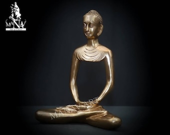 May include: A gold-colored brass statue of a meditating Buddha. The statue is sitting in a cross-legged position with hands resting in the lap.