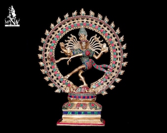May include: A gold-colored statue of the Hindu deity Shiva in the Nataraja pose, dancing on a base with inlaid gemstones. The statue is surrounded by a circular halo with intricate designs and colorful gemstones.