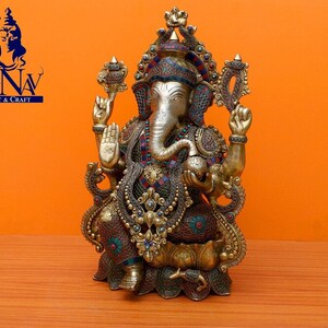 Puede incluir: Una estatua dorada de Ganesha, el dios hind&uacute; de la sabidur&iacute;a y la prosperidad, con detalles intrincados y piedras preciosas de colores. La estatua est&aacute; sentada sobre una base de loto y tiene una trompa, orejas grandes y cuatro brazos.
