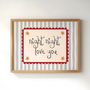 May include: A framed print with a light wood frame. The print has a background of vertical blue and white stripes. A red scalloped border surrounds a cream-colored rectangle with the words "night night love you" in black script, with gold stars.