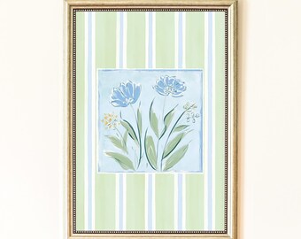 Puede incluir: Impresión artística floral enmarcada. La obra presenta un cuadrado azul claro con dos flores azules y hojas verdes. El fondo tiene un patrón de rayas verdes y blancas. El marco es dorado.
