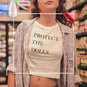 プロテクト・ザ・ドールズ、ヘビーフェードクロップTシャツ、プレミアムレディースファッションTシャツ、カジュアルサマートップス、ヴィンテージスタイルTシャツ、トレンドのストリートウェア、2025年夏
