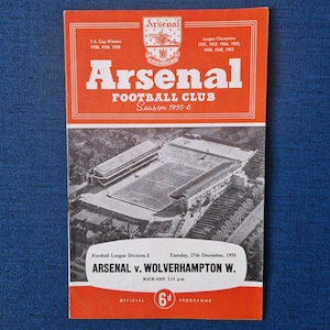 May include: An Arsenal Football Club programme from 27th December 1955. The programme features a photo of the Arsenal stadium and the text "Arsenal v. Wolverhampton W.  Kick-off 2.15 p.m."