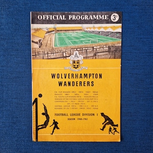May include: A vintage official programme for Wolverhampton Wanderers football club. The yellow cover features a stadium illustration, team name, and season details. The programme is from the 1960-1961 season.