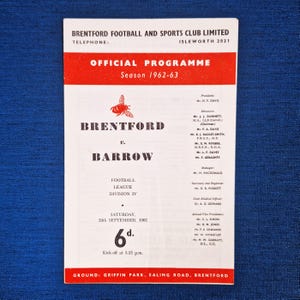 May include: A vintage official matchday programme for Brentford Football Club, season 1962-63. The red and white program details the Brentford versus Barrow match, including the date, time, and price of 6d.