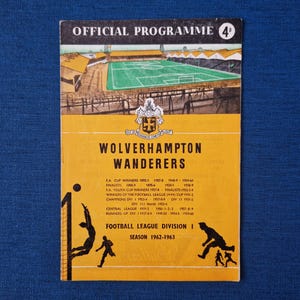 May include: A yellow and black programme for a Wolverhampton Wanderers football match. The programme cover features a drawing of a football pitch and the team's crest. The text on the cover reads "Official Programme 4d" and "Wolverhampton Wanderers". The programme is for the 1962-1963 season.