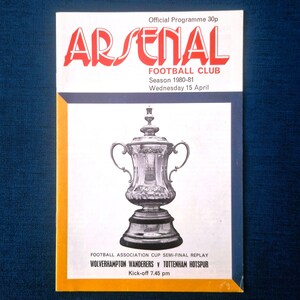 May include: A vintage Arsenal Football Club programme from the 1980-81 season. The cover displays the club's name in red, a silver trophy, and details of a semi-final replay match between Wolverhampton Wanderers and Tottenham Hotspur.