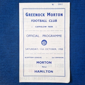 May include: A vintage football programme for Greenock Morton Football Club, with a blue and white design. The programme, dated 11th October 1958, details the match between Morton and Hamilton. Text includes "Official Programme" and "Scottish League 2nd Division".
