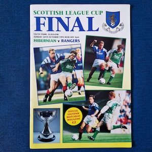 May include: A souvenir matchday magazine for the Scottish League Cup Final. The cover displays action shots of a football match between Hibernian and Rangers. The magazine includes the date, time, and location of the game.