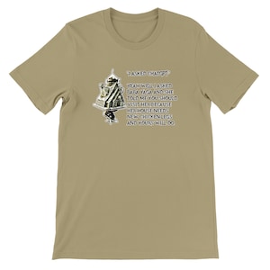 Pode incluir: Camiseta bege de manga curta com o texto "I ASKED CHATGPT" e uma cita&ccedil;&atilde;o humor&iacute;stica sobre Baba Yaga e patas de galinha. O gr&aacute;fico inclui um desenho de uma casa sobre patas de galinha.