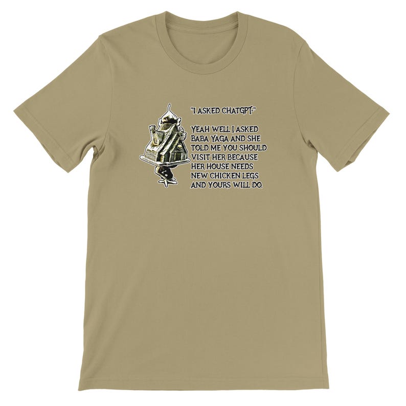Pode incluir: Camiseta bege de manga curta com o texto "I ASKED CHATGPT" e uma cita&ccedil;&atilde;o humor&iacute;stica sobre Baba Yaga e patas de galinha. O gr&aacute;fico inclui um desenho de uma casa sobre patas de galinha.