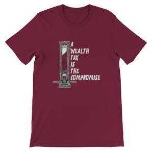 May include: Burgundy t-shirt featuring a guillotine illustration with the text "A Wealth Tax Is The Compromise" in a white, distressed font. The design is centered on the front of the short-sleeved shirt.