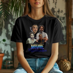 Peut inclure: T-shirt noir avec un graphisme de quatre personnes et le texte "JAVIE Manzoukas" en bleu et blanc. Le design comprend un éclair et une illustration de style portrait.