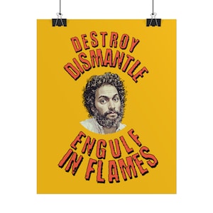 May include: A yellow poster with the words "DESTROY DISMANTLE ENGULF IN FLAMES" in red, stylized text. A man with curly hair and a beard is centered in the poster. The poster is held by two black binder clips.