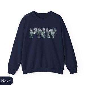 May include: A navy blue sweatshirt with a forest-themed graphic of the letters "PNW" in white.