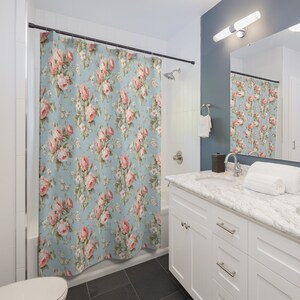 May include: A blue shower curtain with a floral pattern featuring pink roses and green leaves.