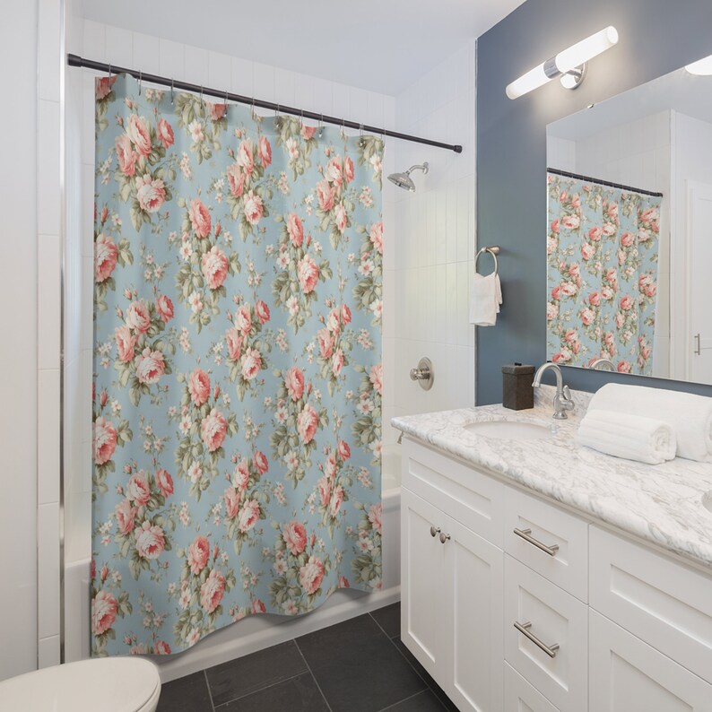 May include: A blue shower curtain with a floral pattern featuring pink roses and green leaves.