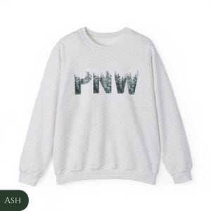 May include: A heather grey sweatshirt with a forest green graphic of the letters "PNW" made up of trees.