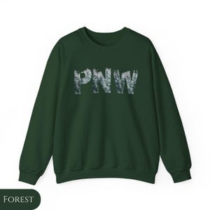 May include: A dark green sweatshirt with the text "PNW" in white letters. The letters are made up of a forest scene.