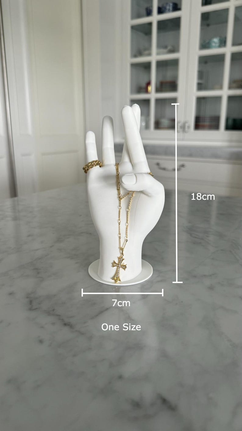 K&ouml;nnte beinhalten: Wei&szlig;er Keramik-Hand-Schmuckhalter mit einer goldenen Kettenkette und einem Kreuzanh&auml;nger. Die Hand ist 18 cm hoch und 7 cm breit. Einheitsgr&ouml;&szlig;e.