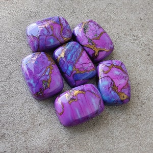 May include: Six purple and blue gemstone cabochons with gold veining. The cabochons are smooth and polished, and they have a variety of shapes and sizes.