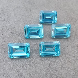 May include: Five light blue rectangular gemstones with a faceted cut.