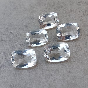 Könnte beinhalten: Sechs klare, rechteckige, facettierte Edelsteine. Die Edelsteine sind in einem Halbkreis auf einer grauen Oberfläche angeordnet.