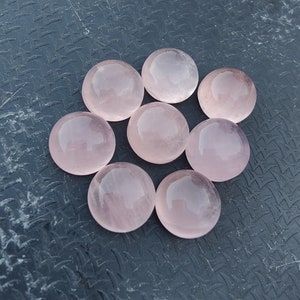 May include: Eight round, smooth, pink rose quartz stones. The stones are polished and have a translucent appearance.