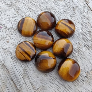 May include: Eight round, polished tiger's eye cabochons in shades of brown and gold. The stones have a chatoyant effect, with a shimmering, iridescent quality.