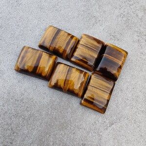 May include: Six polished tiger's eye gemstone squares in various shades of brown and gold.