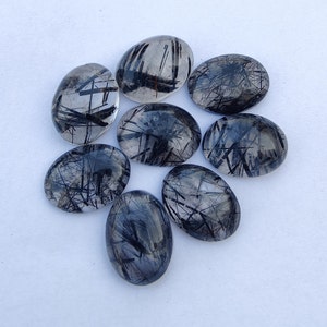 May include: Eight oval-shaped black tourmaline cabochons with a clear quartz matrix. The stones have a translucent appearance with black inclusions.