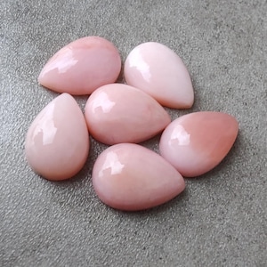 May include: Six teardrop-shaped pink opal cabochons, each with a smooth, polished surface.