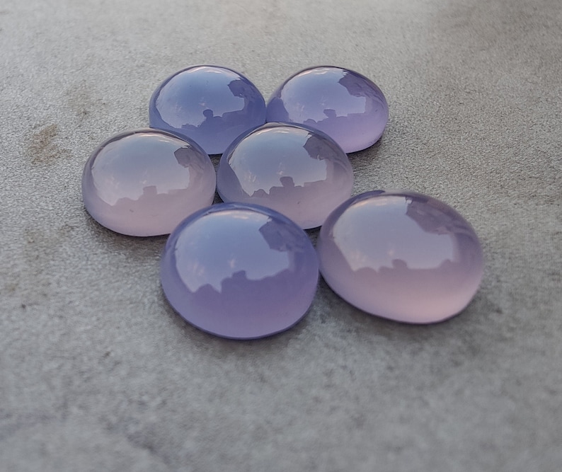 以下が含まれることがあります： 6つの丸い、滑らかな、ラベンダー色の宝石。宝石は半円形に配置されています。