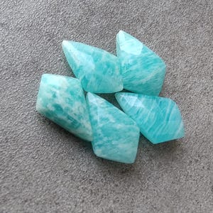 May include: Six teal green amazonite gemstone beads in a faceted, pointed shape.