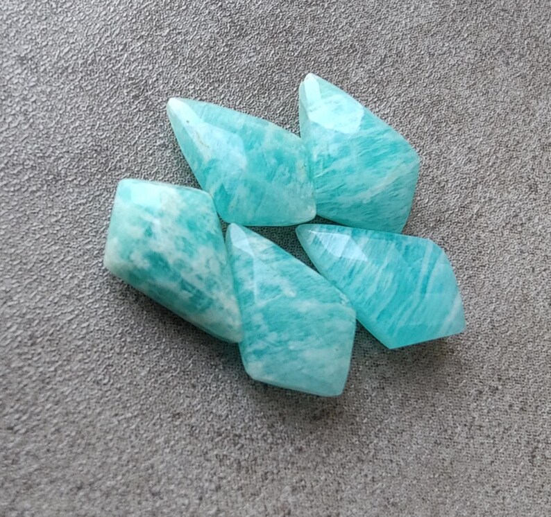 May include: Six teal green amazonite gemstone beads in a faceted, pointed shape.