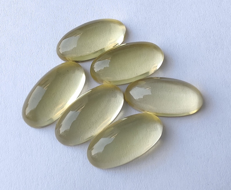 May include: Six oval-shaped, translucent yellow gemstones. The gemstones are smooth and polished.