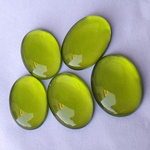 May include: Five oval-shaped green glass stones with a glossy finish.