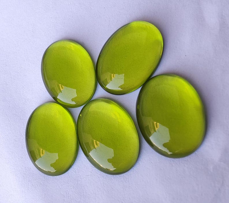 May include: Five oval-shaped green glass stones with a glossy finish.
